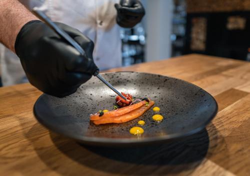 a person in black gloves preparing a plate of food at Caryńska Resort & SPA in Lutowiska