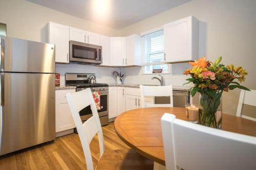 a kitchen with a table and a stainless steel refrigerator at The Boston Rental - Multiple Floorplans in Boston