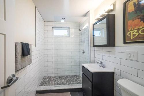 a white bathroom with a sink and a mirror at The Boston Rental - Multiple Floorplans in Boston