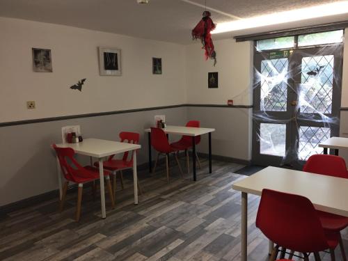 a dining room with white tables and red chairs at Queens Guesthouse Manchester in Manchester