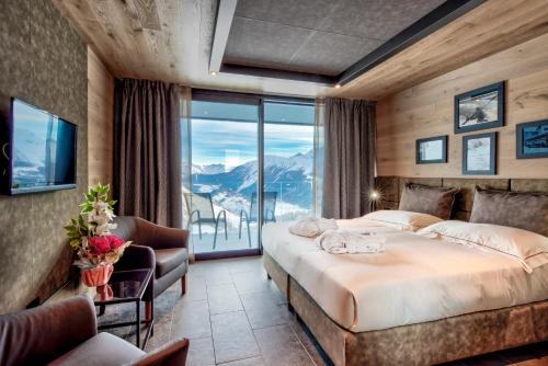 a bedroom with a large bed and a balcony at Re Delle Alpi Resort & Spa, 4 Stelle Superior in La Thuile