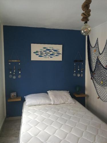 - une chambre avec un lit blanc dans un mur bleu dans l'établissement maison de pêcheur, au Tréport