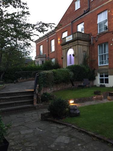 a brick house with a purple light in the yard at Queens Guesthouse Manchester in Manchester
