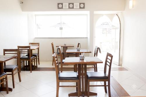 a dining room with tables and chairs and a window at Fenicia Palace Hotel in Varginha