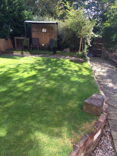 a grass yard with a bench and a gazebo at Queens Guesthouse Manchester in Manchester