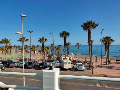 a parking lot next to the ocean with palm trees at Tranquila casa frente al mar in Adra