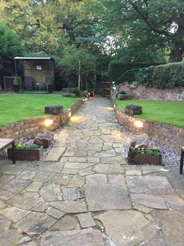 a stone path in a garden with a stone wall at Queens Guesthouse Manchester in Manchester