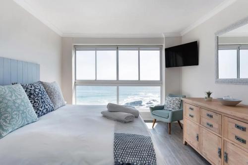 a bedroom with a large bed with a television and a chair at Stunning Views, the Sea & Table Mountain! in Bloubergstrand