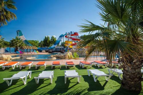 un parque con piscina y una montaña rusa en Camping Club Les Tamaris - Maeva en Le Barcarès