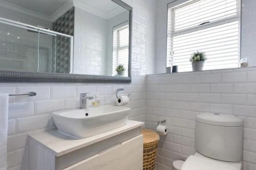 a white bathroom with a sink and a toilet at Stunning Views, the Sea & Table Mountain! in Bloubergstrand