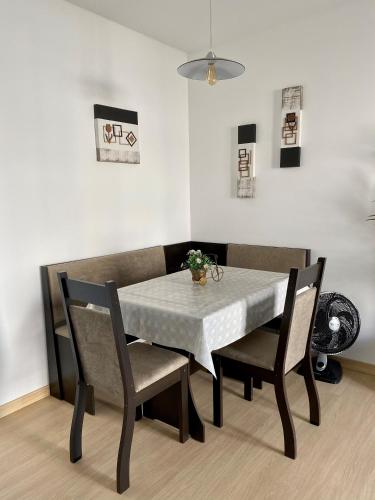 a dining room table and chairs with a white tablecloth at Apart. Manacá (Próximo a pista e rodoviária de Mogi Mirim). in Mogi Mirim