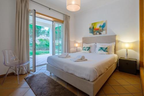 a bedroom with a large bed and a sliding glass door at D. Sebastião Townhouse in Casal da Lagoa Seca