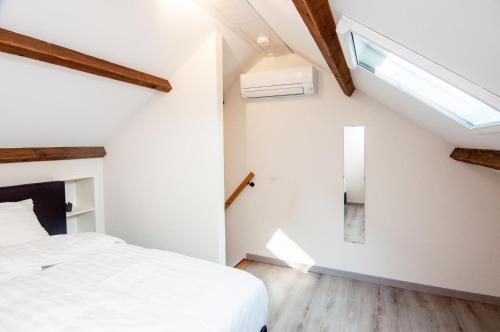 ein Schlafzimmer mit einem weißen Bett und einem Dachfenster in der Unterkunft Vakantiehuis De Bergplaats in Hapert