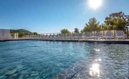 - une piscine avec des chaises longues et le soleil dans l'établissement SOWELL HOTELS La Plage, à Saint-Raphaël