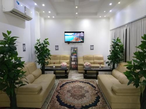 Royal Suite Hotel Apartments في Al Ḩuwayl: غرفة معيشة مع كنب وتلفزيون بشاشة مسطحة