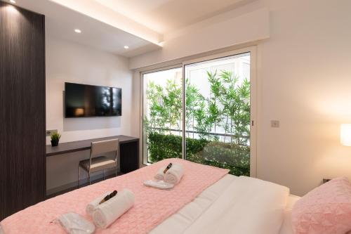 - une chambre avec un lit rose, un bureau et une fenêtre dans l'établissement Blue Dreams YourHostHelper, à Cannes