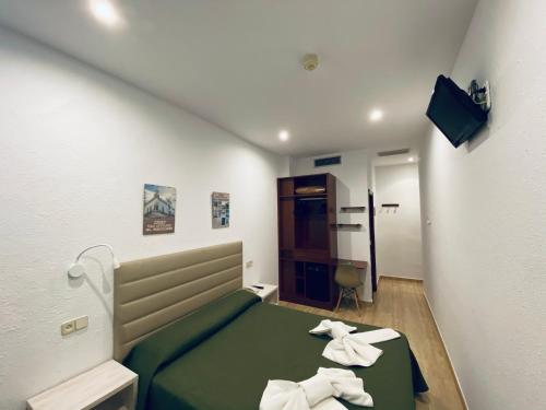 Habitación pequeña con cama verde y toallas. en Hotel Mitus en Canet de Mar