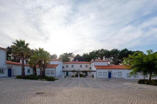 a large white building with palm trees in front of it at Principes Townhouse in Casal da Lagoa Seca