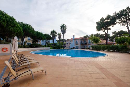 a swimming pool with two lounge chairs and a house at Principes Townhouse in Casal da Lagoa Seca