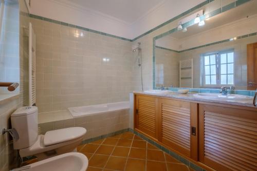 a bathroom with a toilet and a sink and a tub at Principes Townhouse in Casal da Lagoa Seca