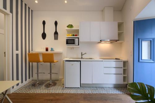 a kitchen with white cabinets and white appliances at Alfama Yellow House in Lisbon