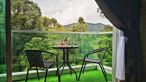 Una mesa y dos sillas frente a una gran ventana. en My Cool Home x The Quintet @ Cameron Highlands, en Tanah Rata
