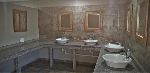 a bathroom with three sinks and two mirrors at Milorho Lodge in Rietfontein