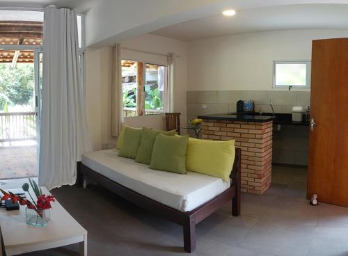 a living room with a couch with green pillows at Pousada Tubes Maresias in Maresias