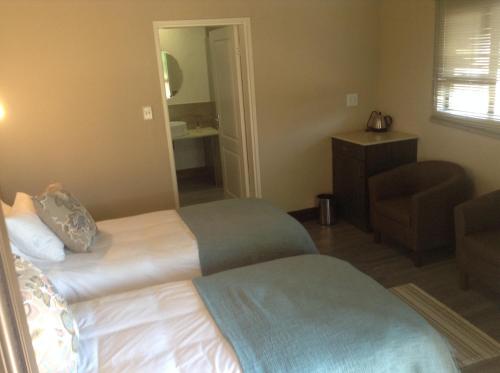 a hotel room with two beds and a chair at Jock of the Bushveld in Barberton