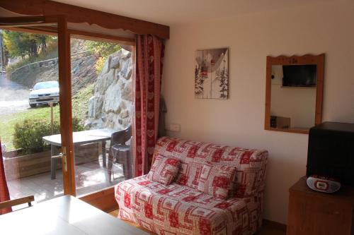 uma sala de estar com um sofá e uma porta de vidro deslizante em Appartement Puy Saint Vincent 1800 - 6 personnes em Puy-Saint-Vincent