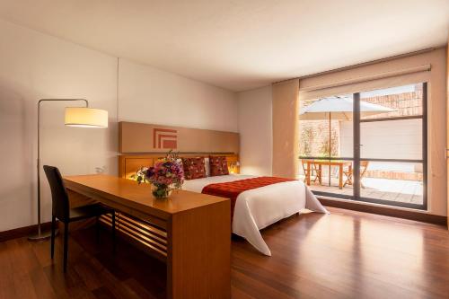 ボゴタにあるHotel bh La Quintaのベッドルーム1室(ベッド1台、テーブル、デスク付)