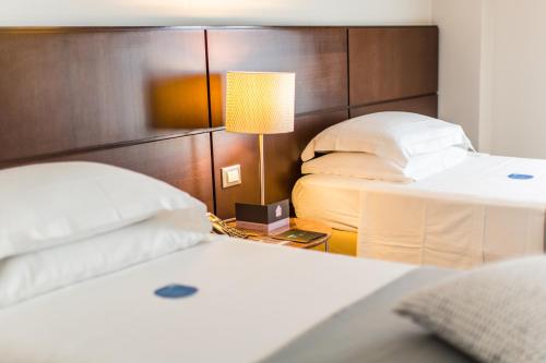 a bedroom with two beds and a table with a lamp at Hotel Casali in Cesena