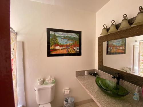 a bathroom with a sink and a toilet and a mirror at Villa Rosa Inn in Santa Barbara
