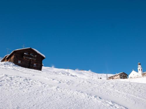 a wooden building on top of a snow covered slope at Bait Nof - Trepalle in Livigno