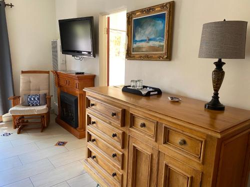 a room with a wooden dresser with a tv on the wall at Villa Rosa Inn in Santa Barbara