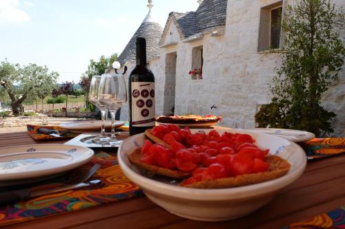 a table with a bowl of tomatoes and a bottle of wine at IL VIGNETO SOLE&LUNA con PISCINA PRIVATA in Martina Franca