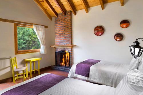 1 dormitorio con 2 camas y chimenea en Cabañas Sierra Mazamitla, en Mazamitla