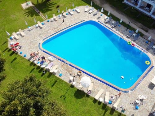 an overhead view of a large swimming pool with people sitting around it at Anna Apartments in Acharavi