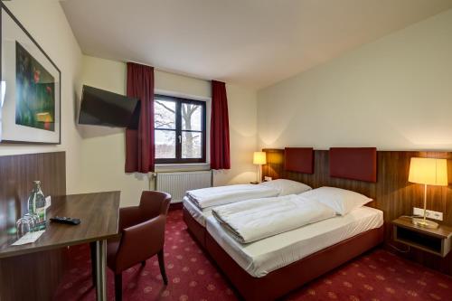 a hotel room with two beds and a desk at Cavallestro Classic in Kitzingen