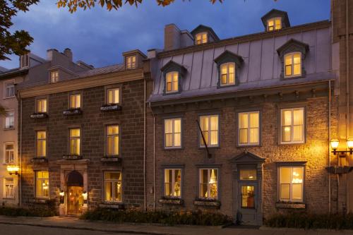 a large brick building with lit windows at night at Hotel Manoir D'Auteuil in Quebec City