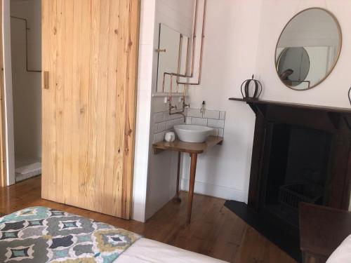 a bathroom with a sink and a mirror next to a fireplace at At The Loerie in Knysna
