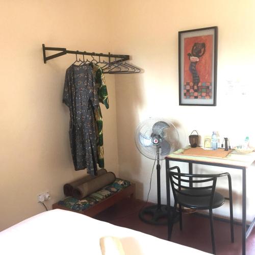 a room with a desk and a dress hanging on a wall at Carpe Diem Guesthouse in Entebbe