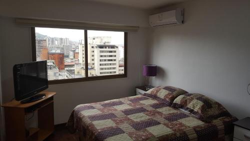 1 dormitorio con 1 cama, TV y ventana en Apartosuites cerca del Boulevar de Sabana Grande y la Av. Solano, en Caracas