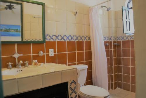 a bathroom with a sink and a toilet and a mirror at Hotel Belmar in Isla Mujeres