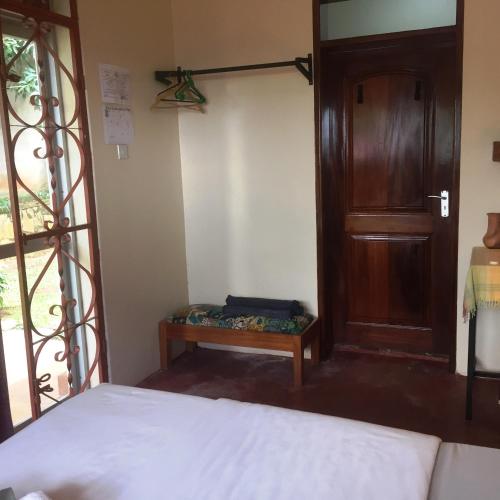 a bedroom with a bed and a wooden door at Carpe Diem Guesthouse in Entebbe