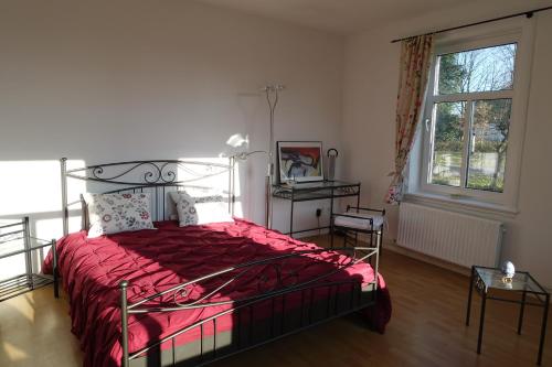 ein Schlafzimmer mit einem Bett mit einer roten Bettdecke und einem Fenster in der Unterkunft Hotel Alpenblick in Todenbüttel