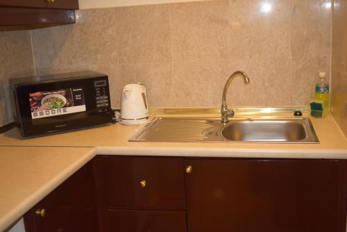 a kitchen counter with a sink and a microwave at Grand Service Apartment @ Times Square in Kuala Lumpur