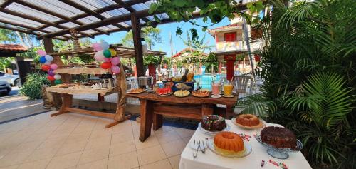a table with cakes and pastries on top at Hotel Ferrugem Eco Village in Garopaba