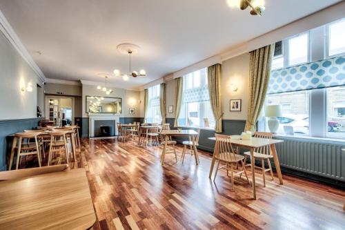 a restaurant with wooden tables and chairs and windows at The Castle Hotel in Berwick-Upon-Tweed