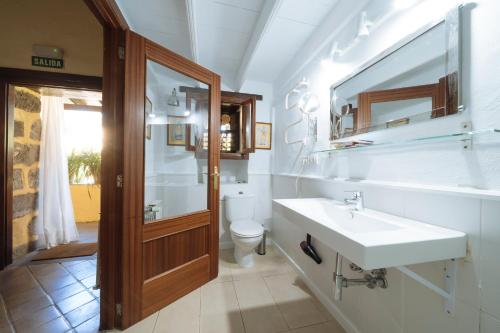 a bathroom with a sink and a toilet and a mirror at Hotel Rural Las Calas in Vega de San Mateo